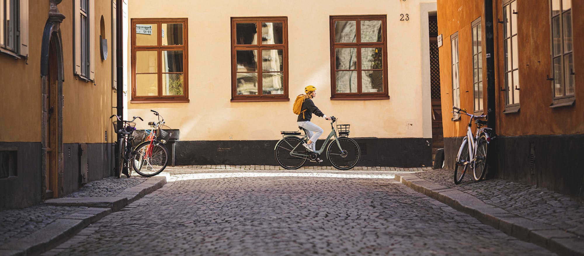 Kvinna cyklar genom pittoresk stad (Crescent)