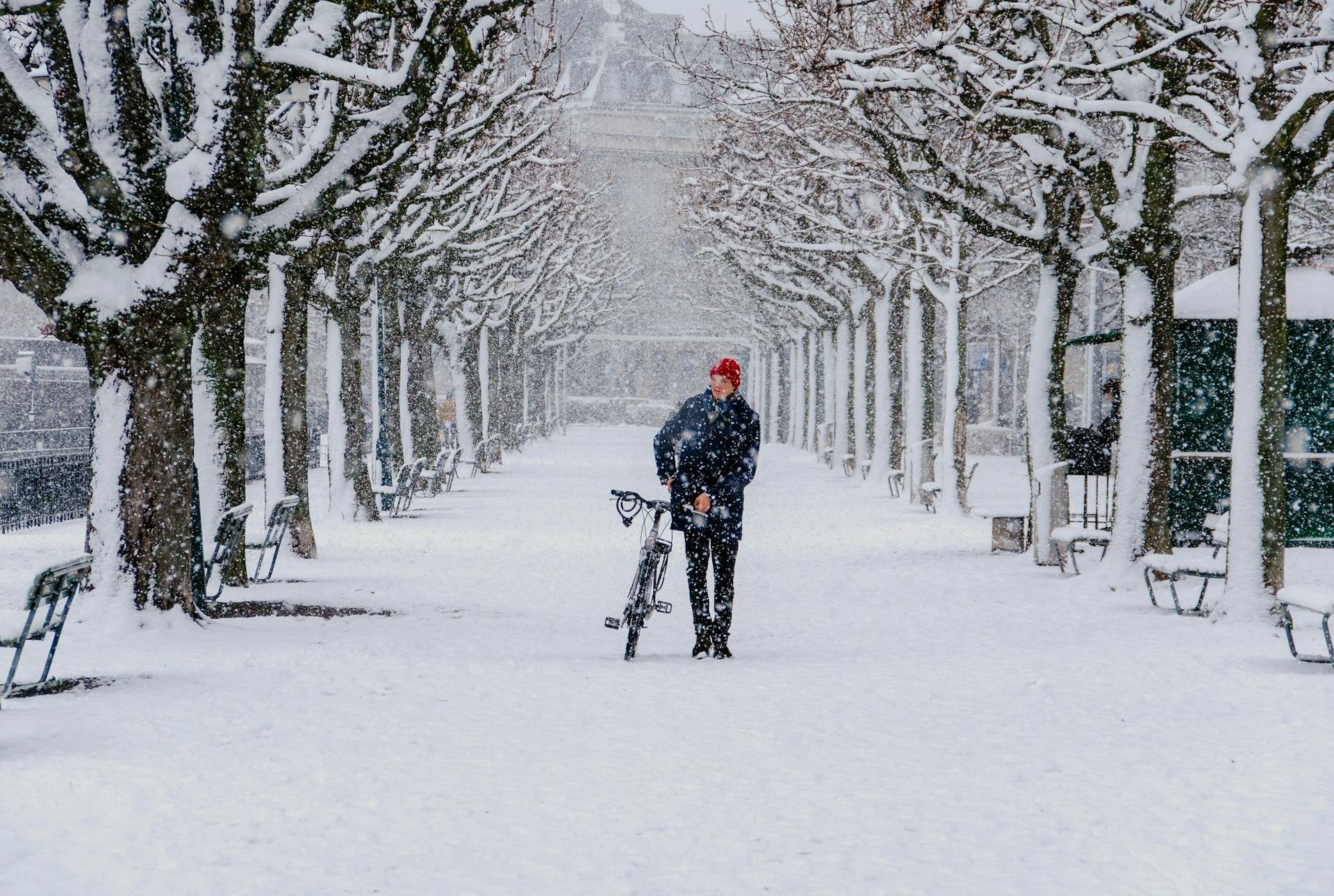 Man går i snön med sin cykel (unsplash)